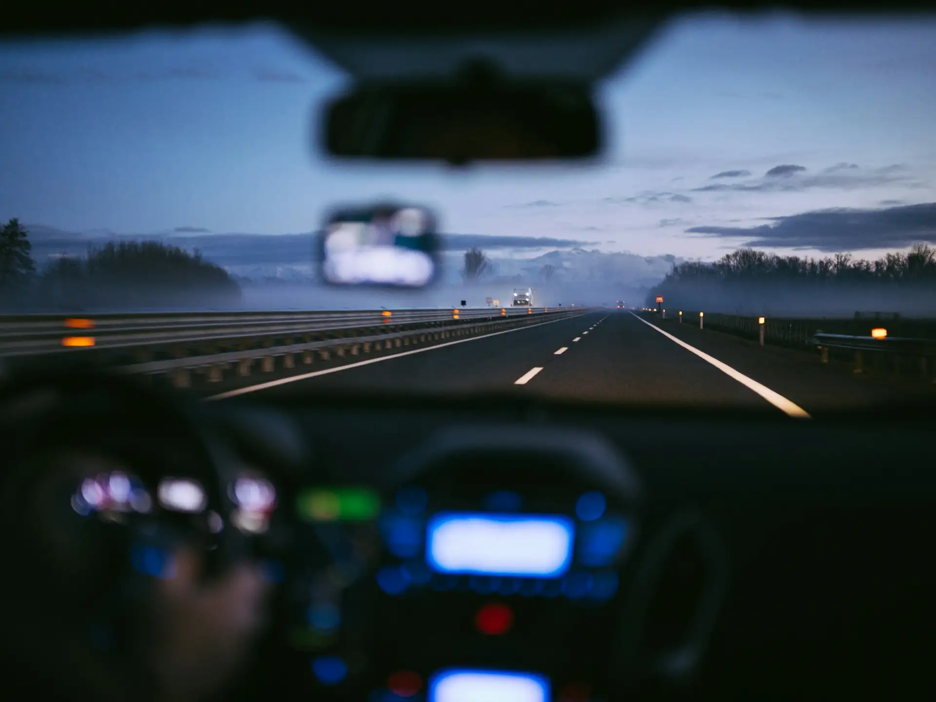 Blick durch die Windschutzscheibe auf eine Autobahn im Morgennebel